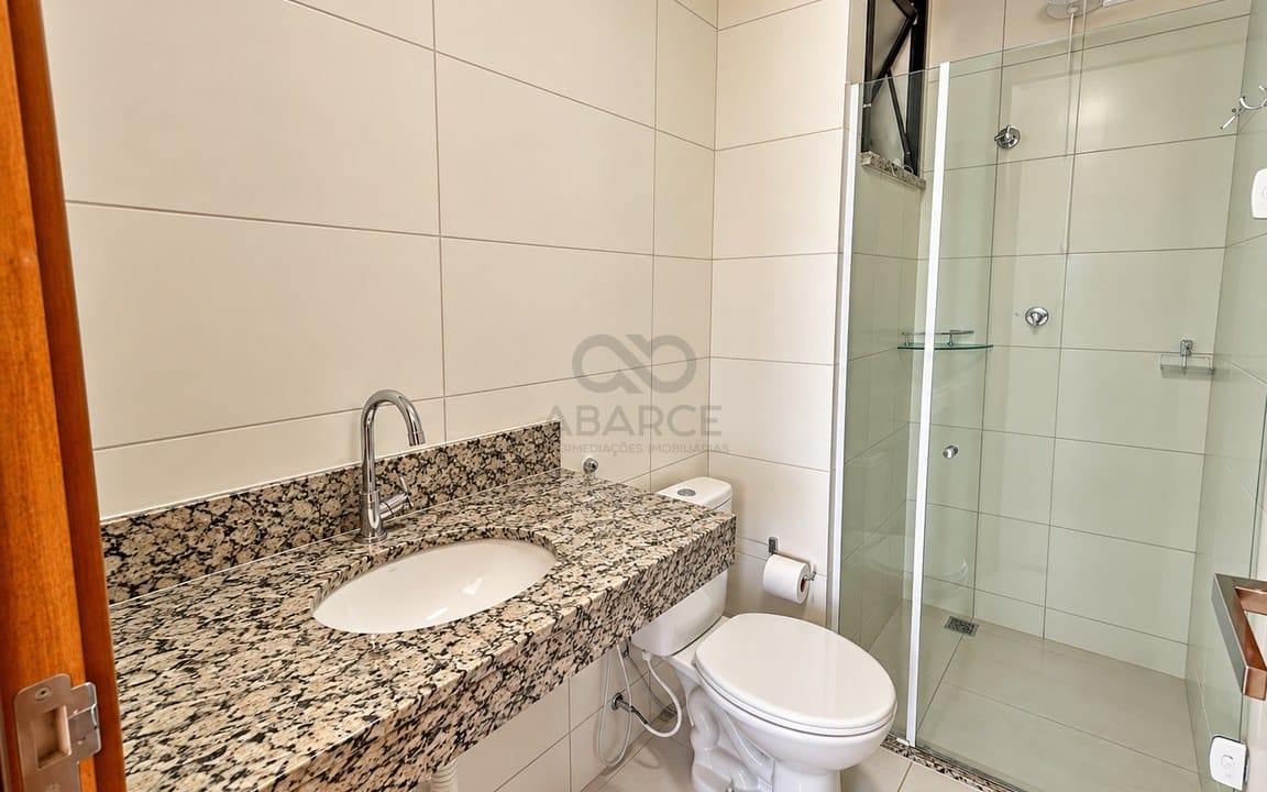 Banheiro moderno com bancada de granito e box de vidro.jpg
